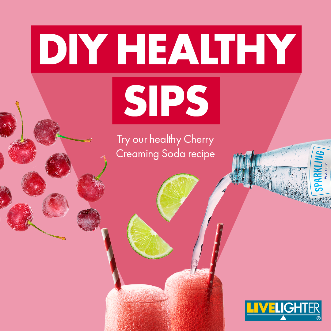 Frozen cherries, lime wedges and sparkling water float in the air over two tall glasses of a red fizzy drink. The heading reads 'DIY healthy sips'. The subheading reads 'Try our healthy cherry creaming soda recipe.'