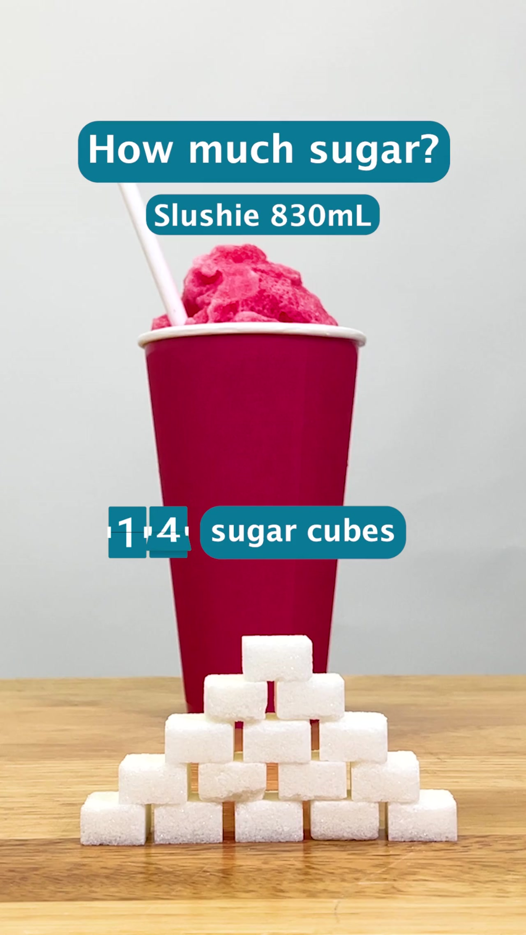 A large takeaway cup with red slushie. Sugar cubes are stacked in front and a counter on screen says 14 sugar cubes.