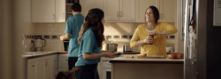 Wide shot of kitchen where two children in school uniform are helping their mum to make dinner. Still shot from the menu app campaign advertisement.