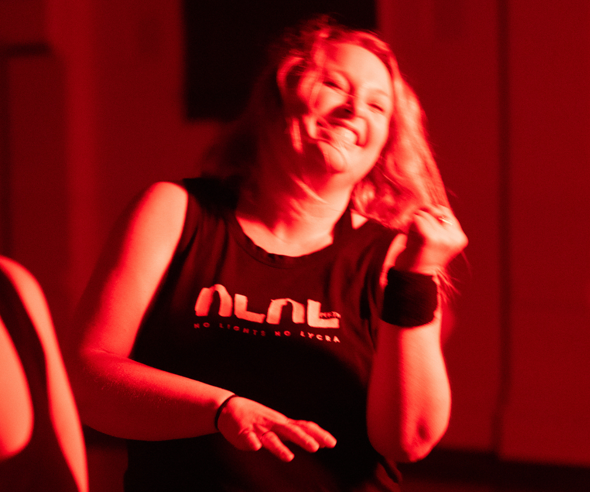 Woman dances with joy in a room bathed in red light.