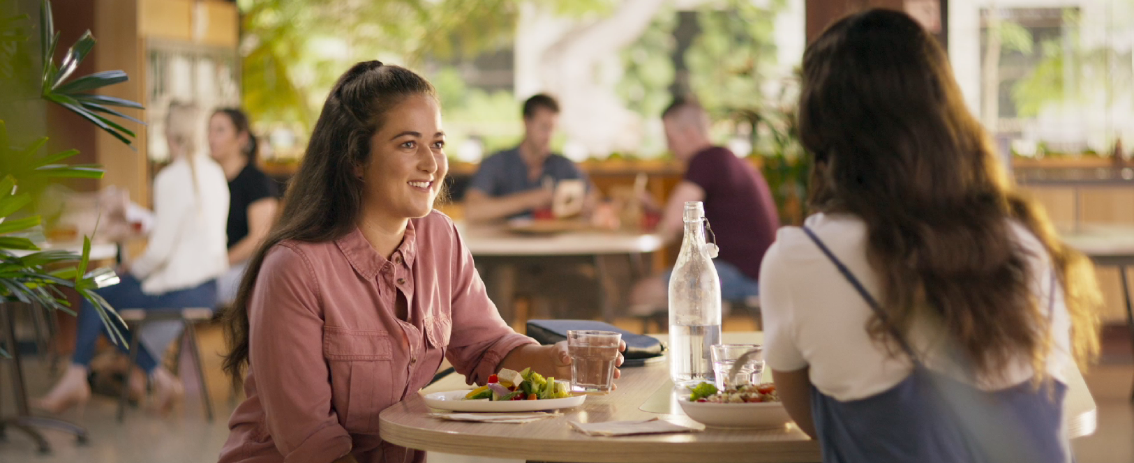 Friends drink water and have lunch at a food court