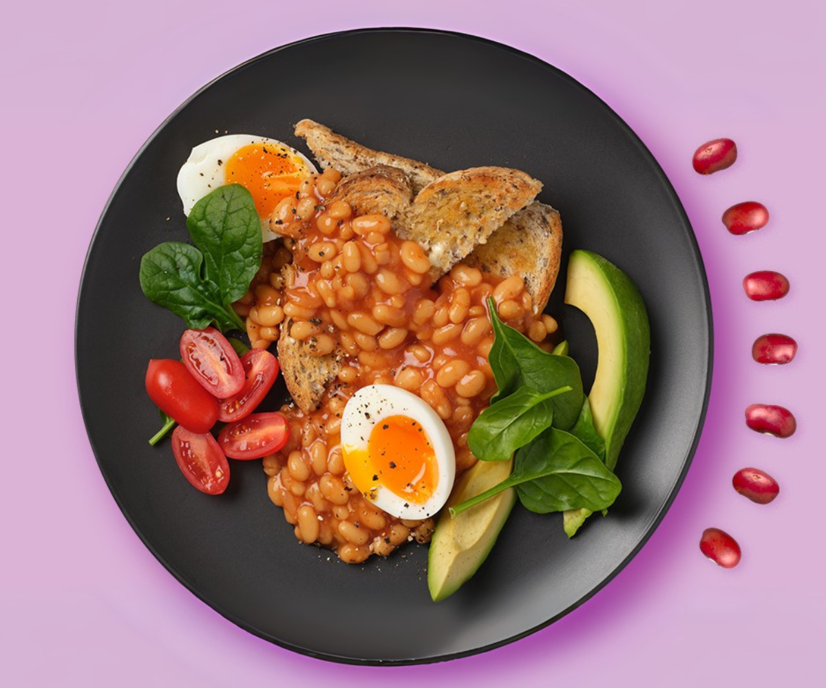 Big breakfast plate featuring grainy toast, eggs, spinach, cherry tomatoes, avocado and baked beans