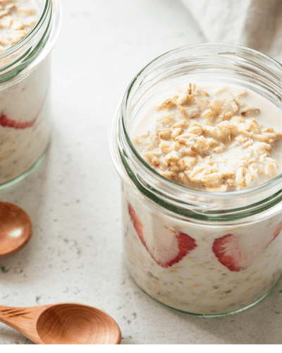 An open jar containing leftor porridge and sliced strawberries