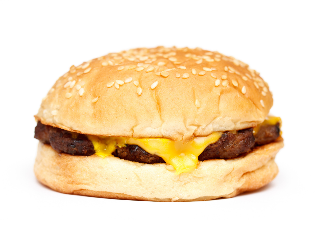 Fast food burger made with a white roll, meat patty and a square of bright yellow cheese.