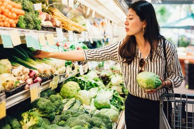 Woman holds a cabbage at the grocery store