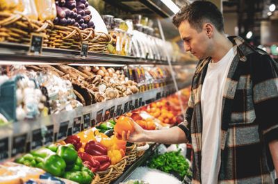 Man chooses a capsicum at the grocery store