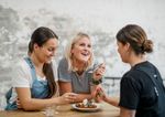 Three young women smile as they share a piece of cake