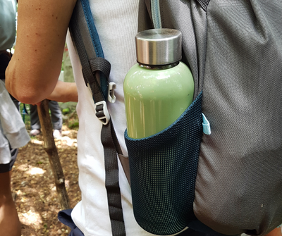 A green metal water bottle in a backpack water bottle holder   