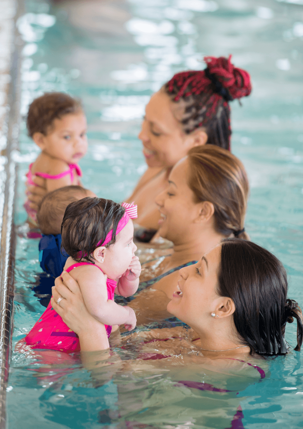 three women hold their babies in the pool