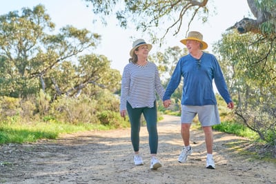 Man and woman walk along a bush trail holding hands