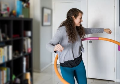 young woman hula hooping in her lounge room 