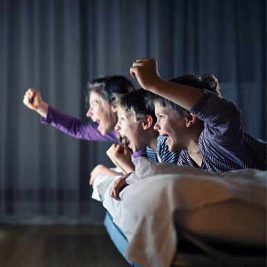 an adult and 2 children lying on a bed and cheering