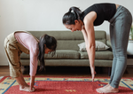 mother and daughter stand and stretch to reach their toes