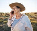 A woman wearing work gear stands in a paddock talking on the phone