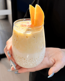 Glass with sago and milk in the bottom, topped with creamy blended mango with a mango slice as a garnish