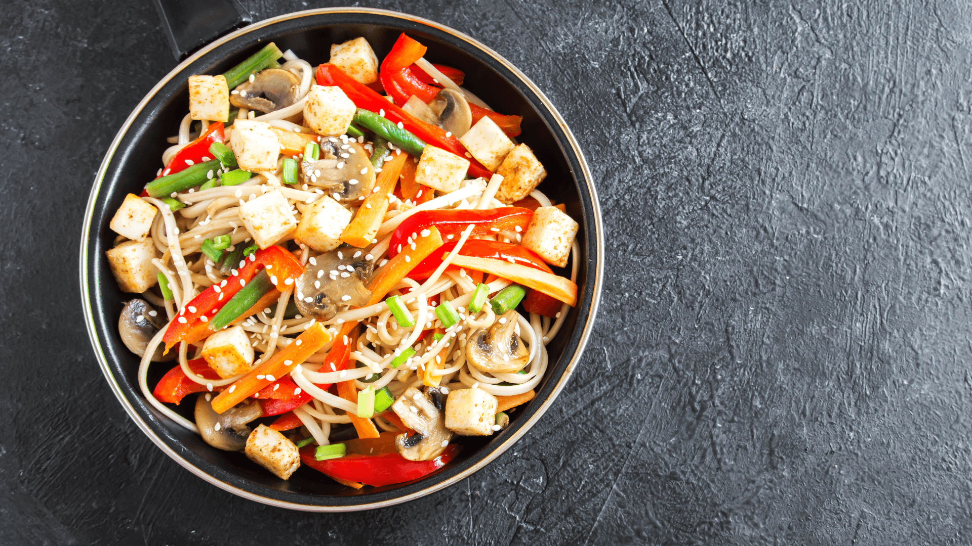 A colourful bowl of tofu, mushrooms, red capsicums and noodles