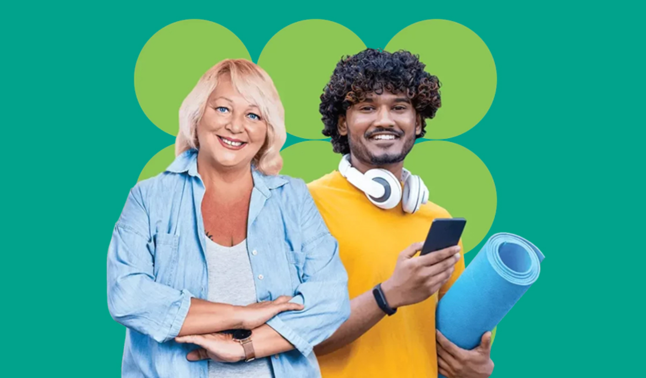 two people smiling at the camera. One is holding an excercise mat and their phone