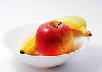 An apple and a banana sit in a small white ceramic bowl