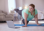 A young woman does core exercises demonstrate on a laptop