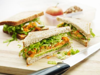 Wholemeal bread filled with cheese and fresh salad on a chopping board